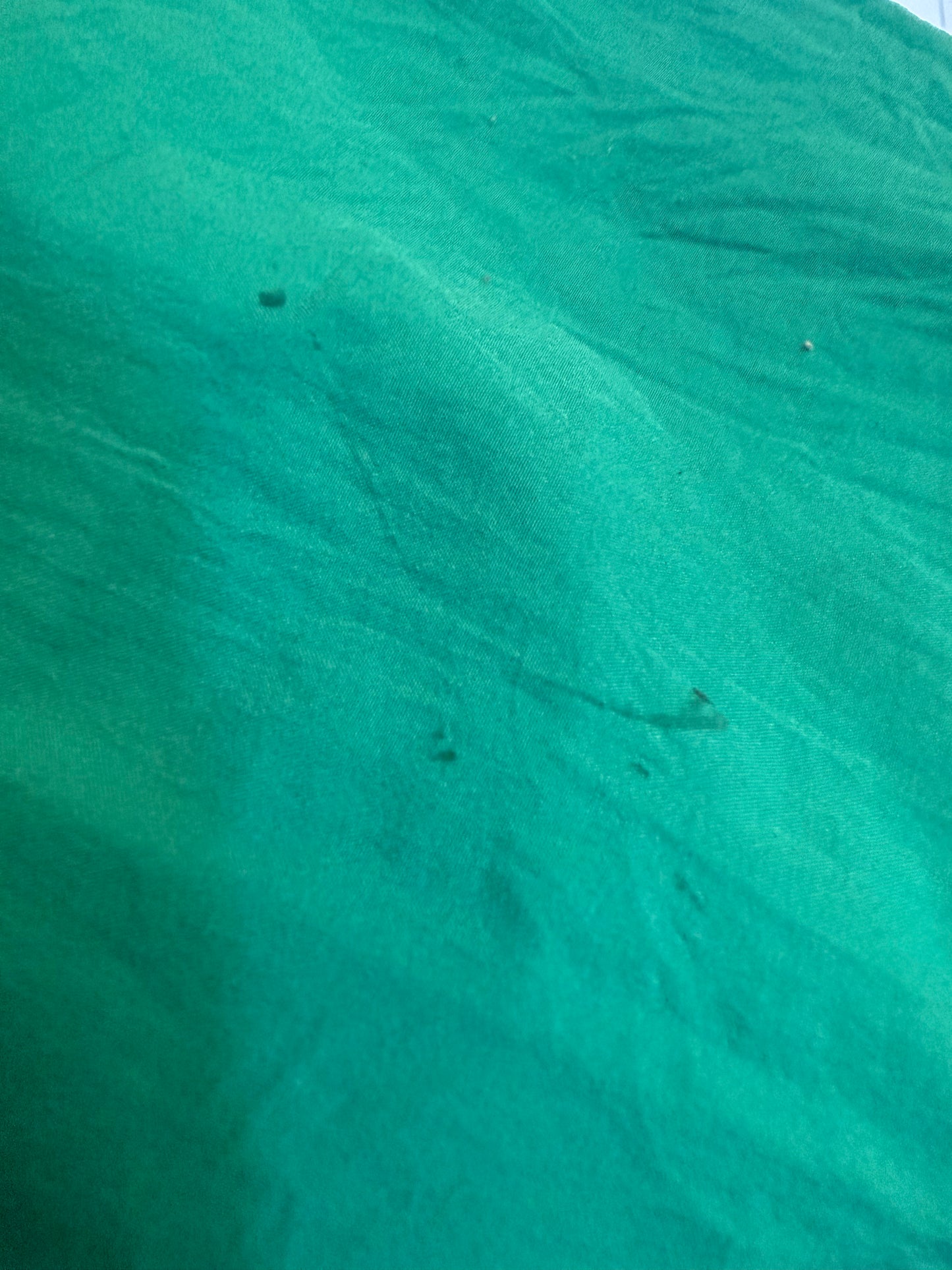 Close-up of green fabric with visible texture and small pen markings. Not sure if these will come out with stain removal treatment, but they are hardly noticeable especially when wearing.