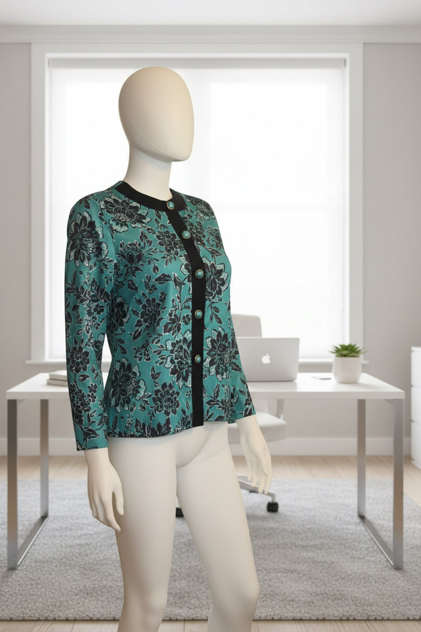 Mannequin wearing a teal floral-patterned jacket in a room with a plant and furniture.