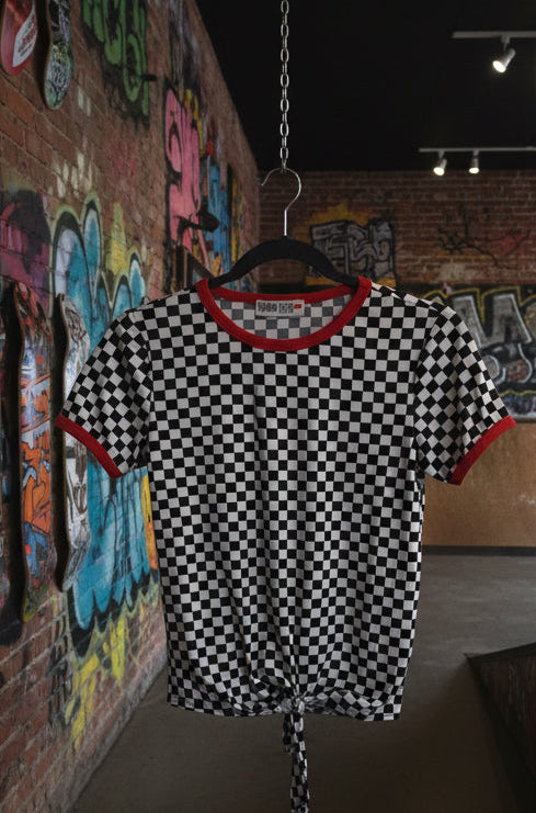 Black and white checkered shirt with red trim on a hanger in a room.