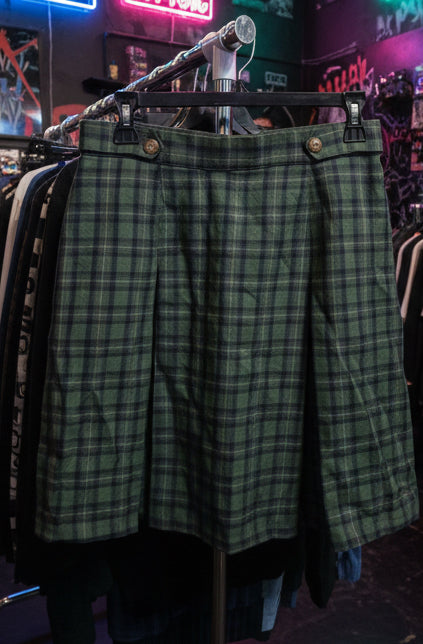 Green plaid pants on a hanger with a colorful shirt in the background