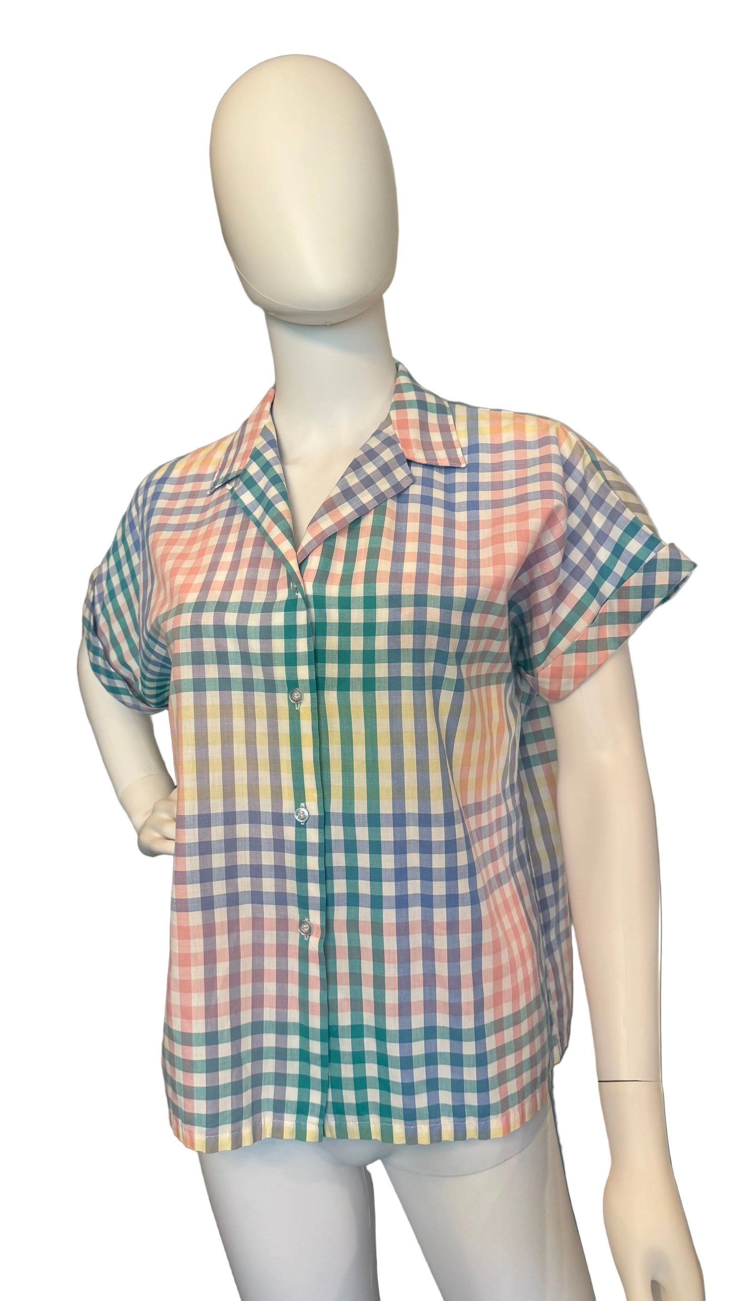 Mannequin wearing a colorful checkered shirt in a room with a ceiling fan.