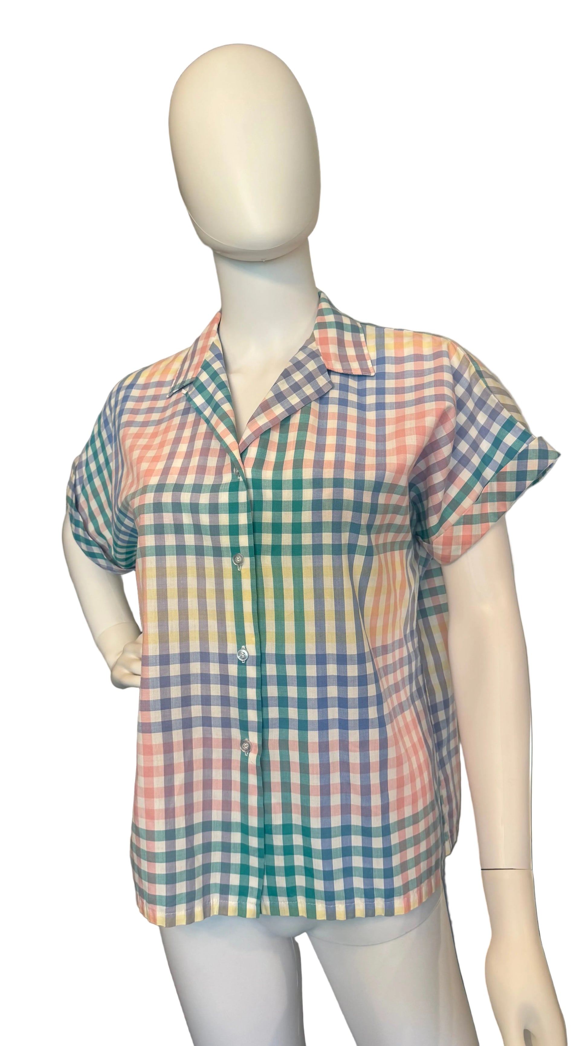 Mannequin wearing a colorful checkered shirt in a room with a ceiling fan.