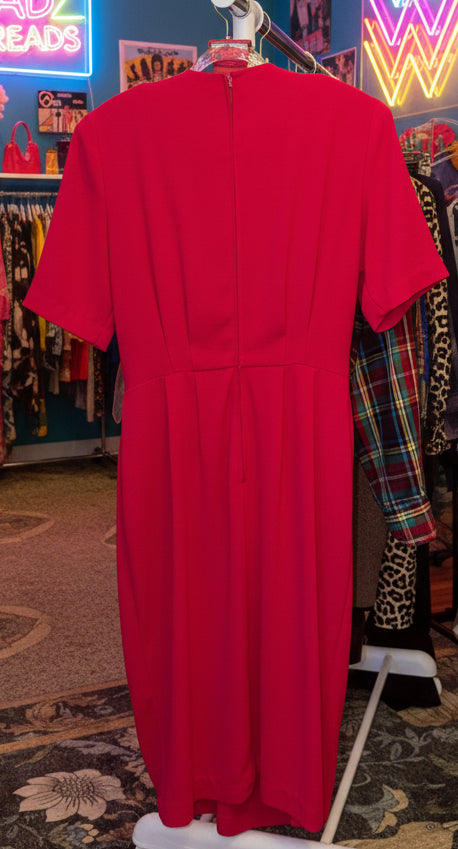 Red dress on a hanger in a room with other clothing in the background